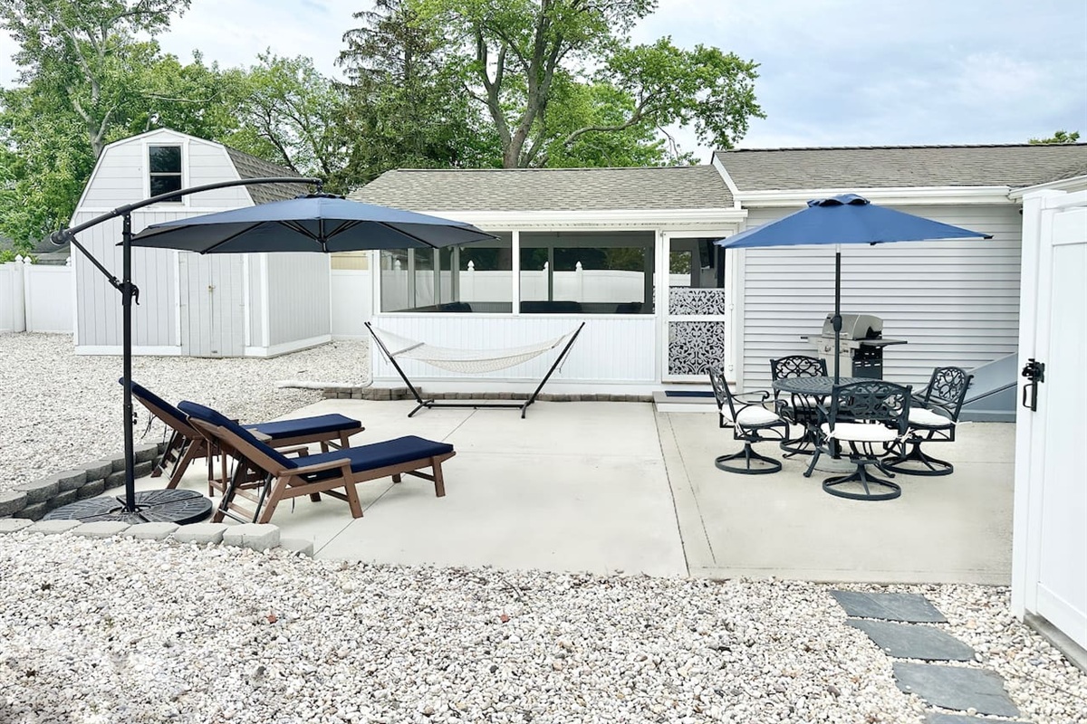 Maximize your vacation in our fully equipped backyard. Features include a gas grill, patio dining for four under a blue umbrella, lounge chairs for sunbathing, and a relaxing hammock. The perfect setup for a summer afternoon BBQ!