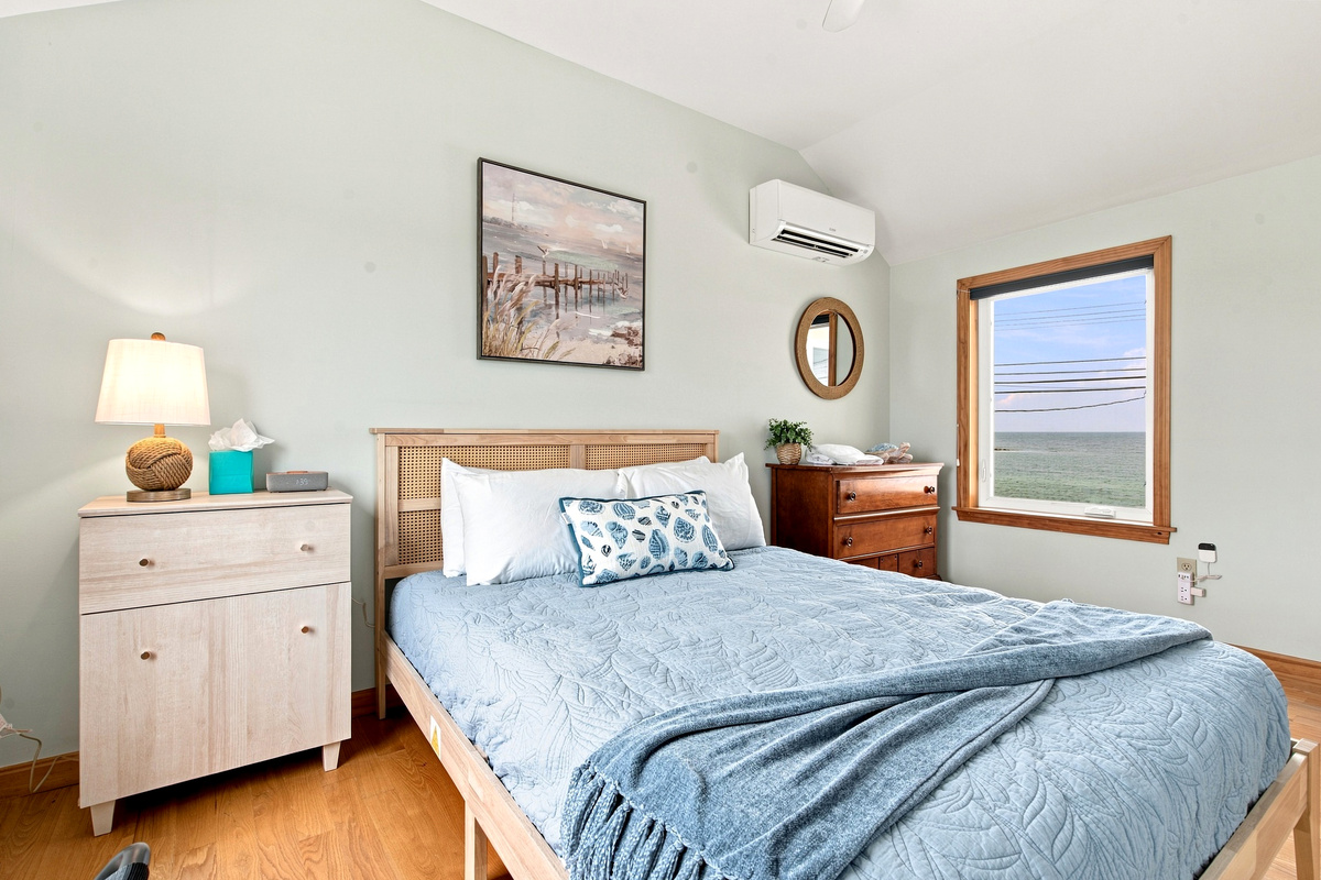 Bright and inviting bedroom featuring a queen bed, vaulted ceilings, and a relaxing atmosphere.
