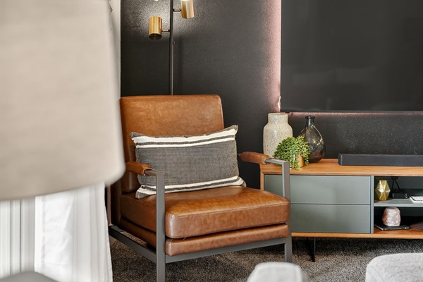 Designer leather armchair and console styling with plants, throws, and curated accessories.