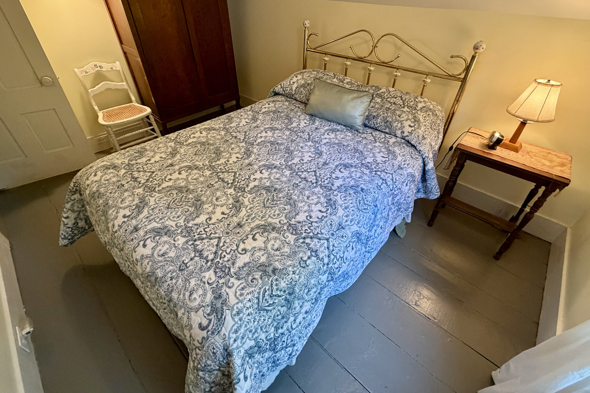 The guest bedroom features a handsome antique wardrobe, offering ample storage space for your belongings. This cozy room beautifully pairs original charm with functional modern comfort for a restful stay near Acadia.