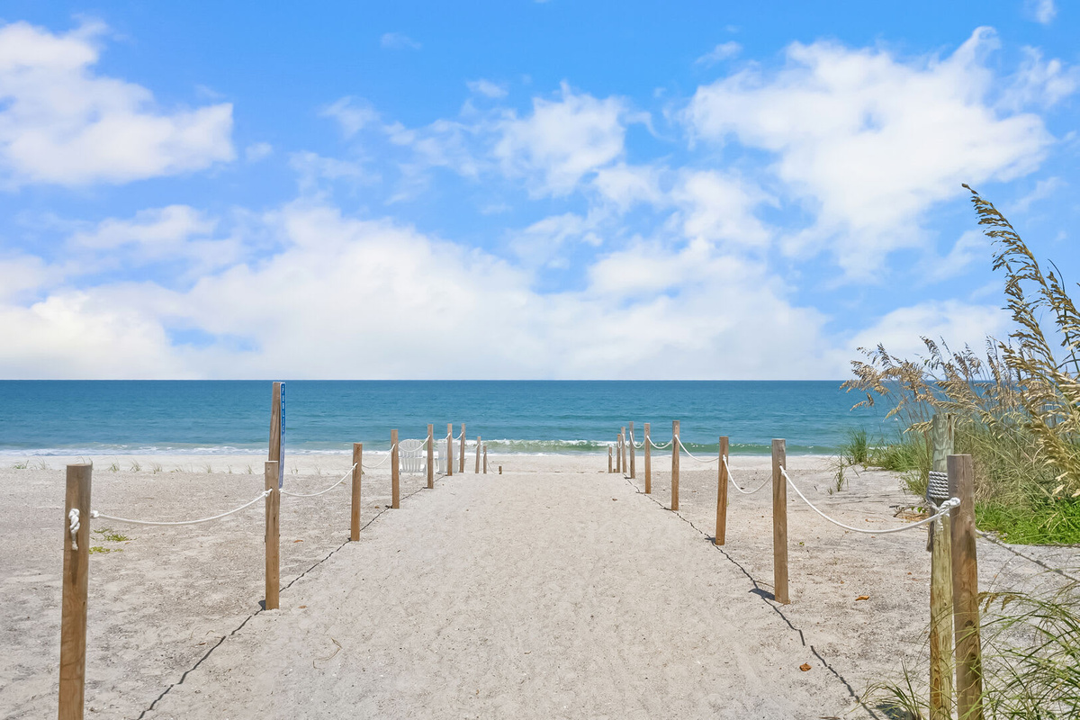 The beach access walkover is across Coastal Highway, roughly a three-minute walk from the front door. Towels over shoulders, flip-flops in hand, and the Atlantic opening up at the end of the boardwalk.