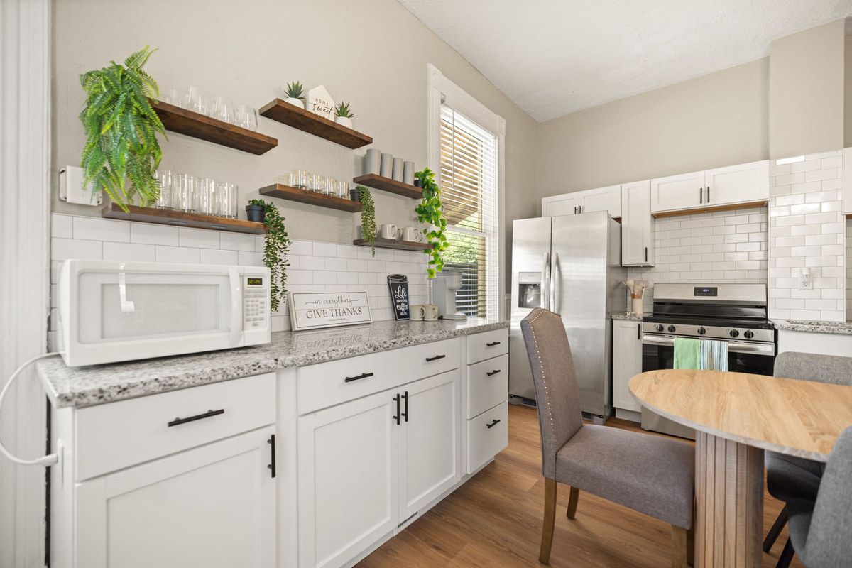 Stylish kitchen with open wood shelving, lush greenery, and a warm, inviting atmosphere