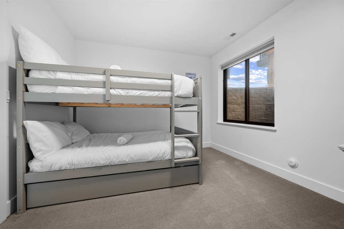 Lower-level bunk room with queen-over-queen bunk bed and twin trundle.