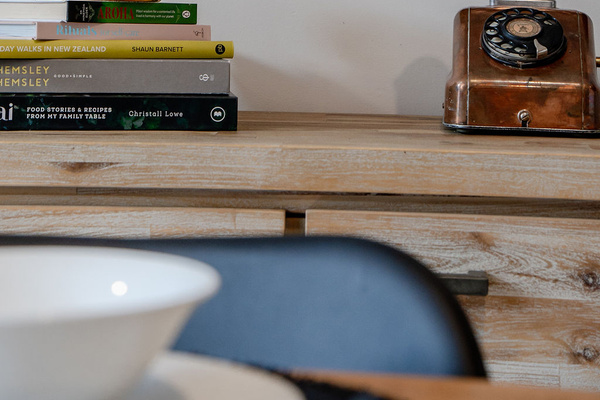 Fernhill Mountain Escape’s dining detail adds warmth to the Queenstown stay, with books, timber texture and character styling beside the table.
