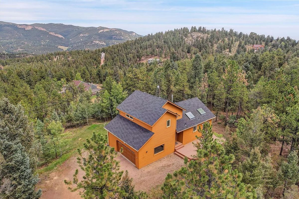 Aerial view showcasing the roofline, exterior siding, and surrounding trees.