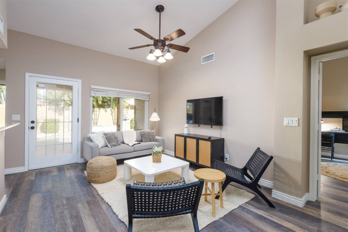 Sitting area with wall-mounted TV, comfortable seating, ceiling fan, and patio door access for relaxed downtime.
