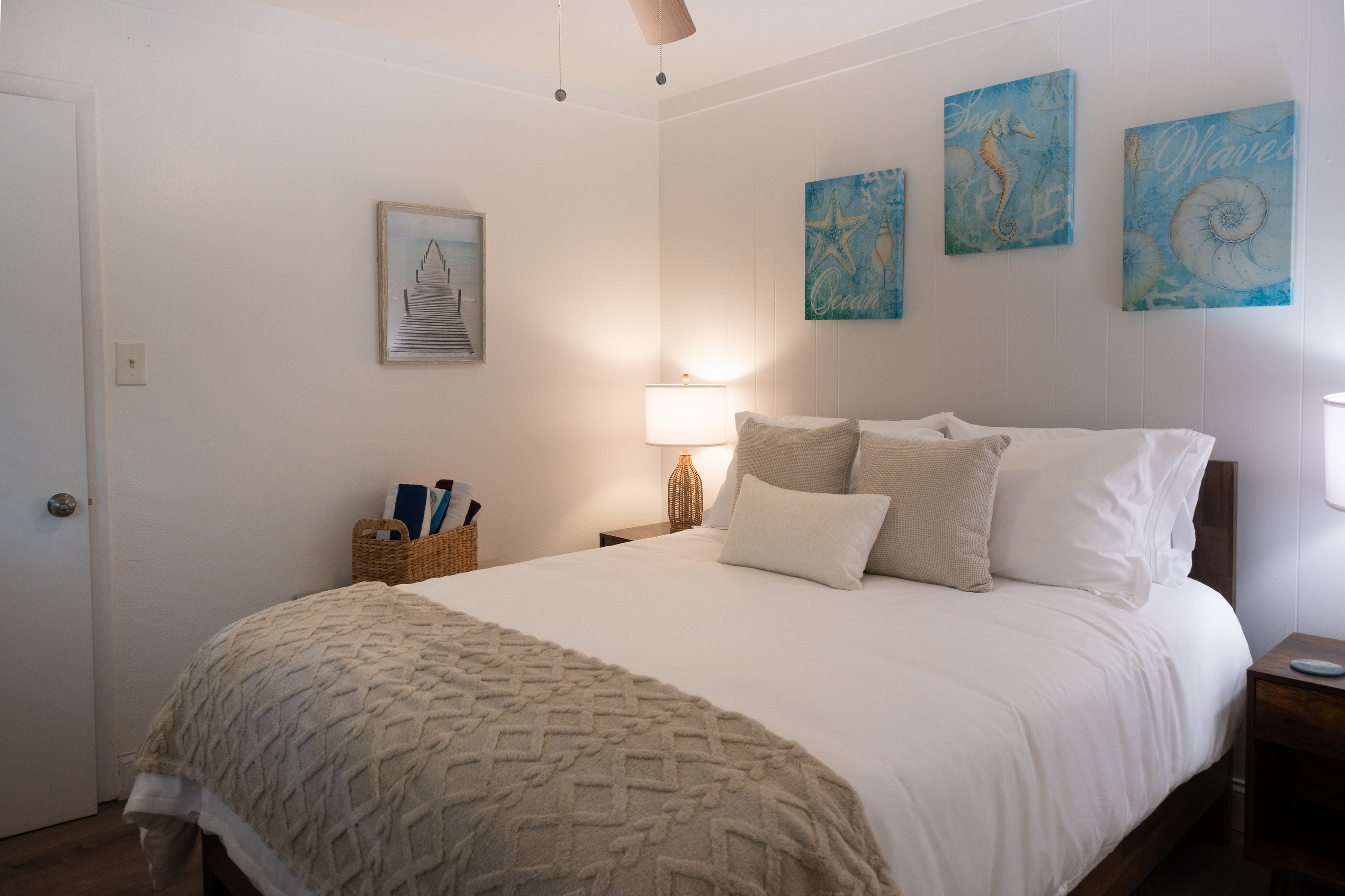 Queen bed with crisp hotel-quality linens and soft coastal art