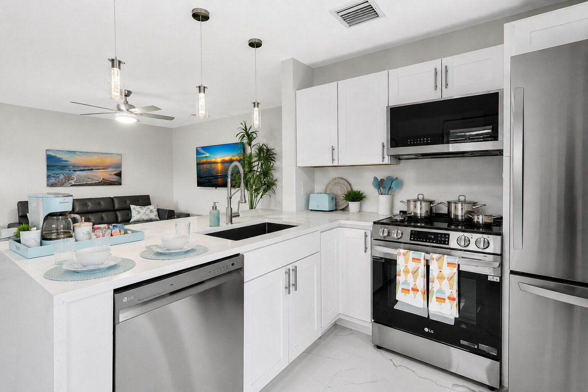 Fully stocked kitchen with stainless steel LG appliances, gas range, dishwasher, ample counter space, and a coffee station. The peninsula provides additional seating and opens directly to the living area.
