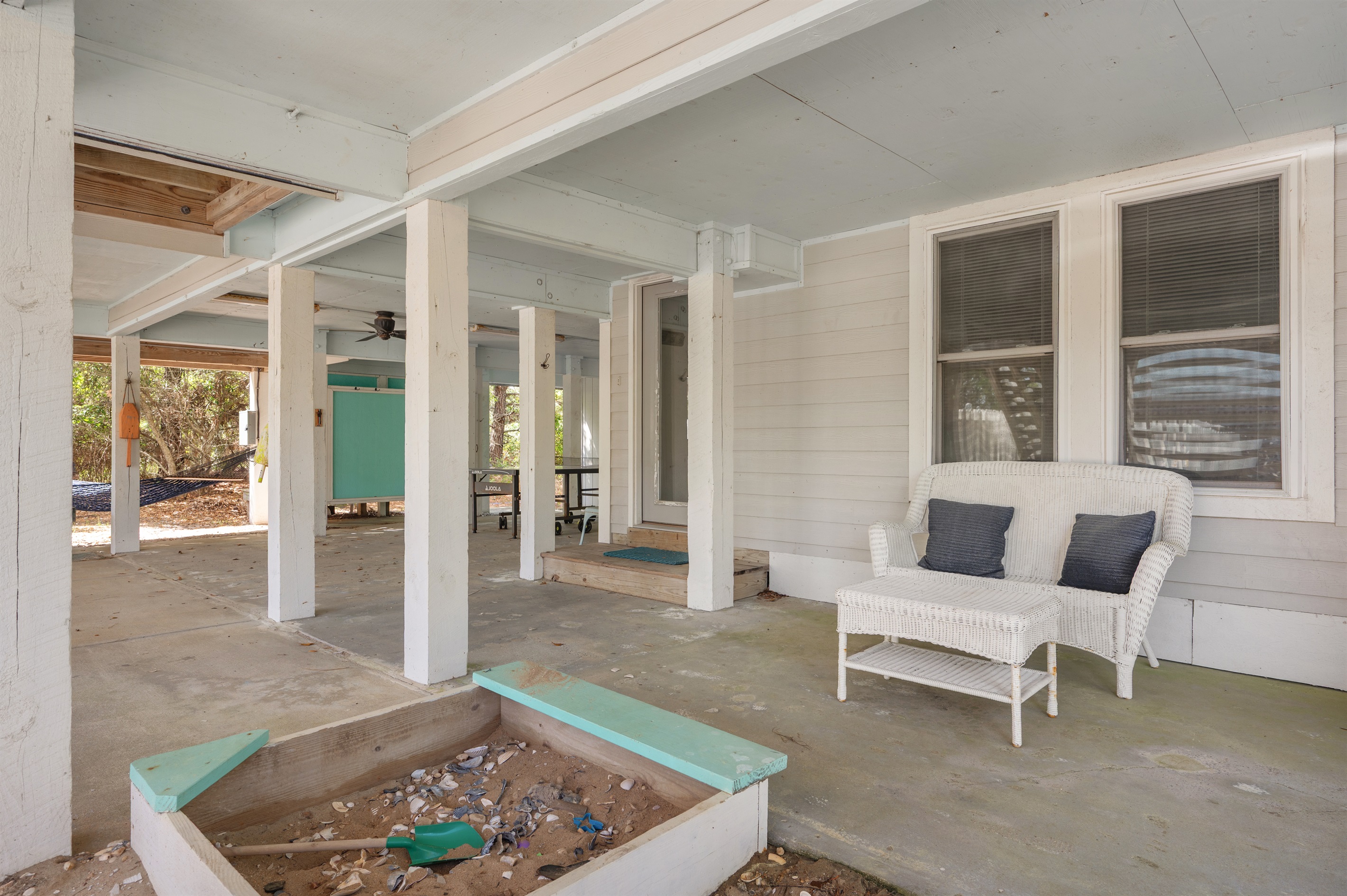 Covered outdoor lounge space with shaded seating and a kids’ sandbox for extra family fun.