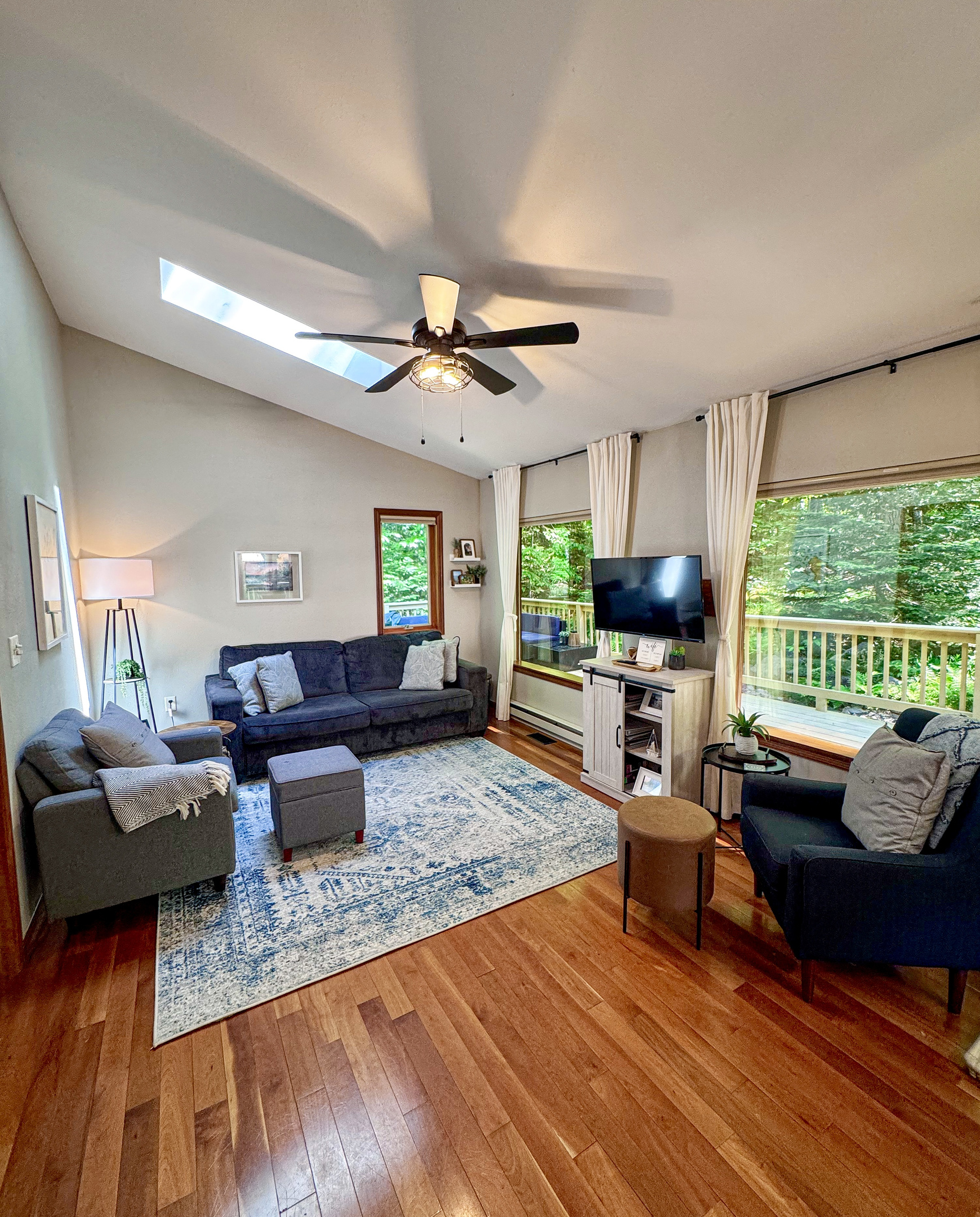 Living room with panoramic mirror reflective windows overlooking the woods, vaulted ceilings with skylight lots of natural light, propane fireplace 