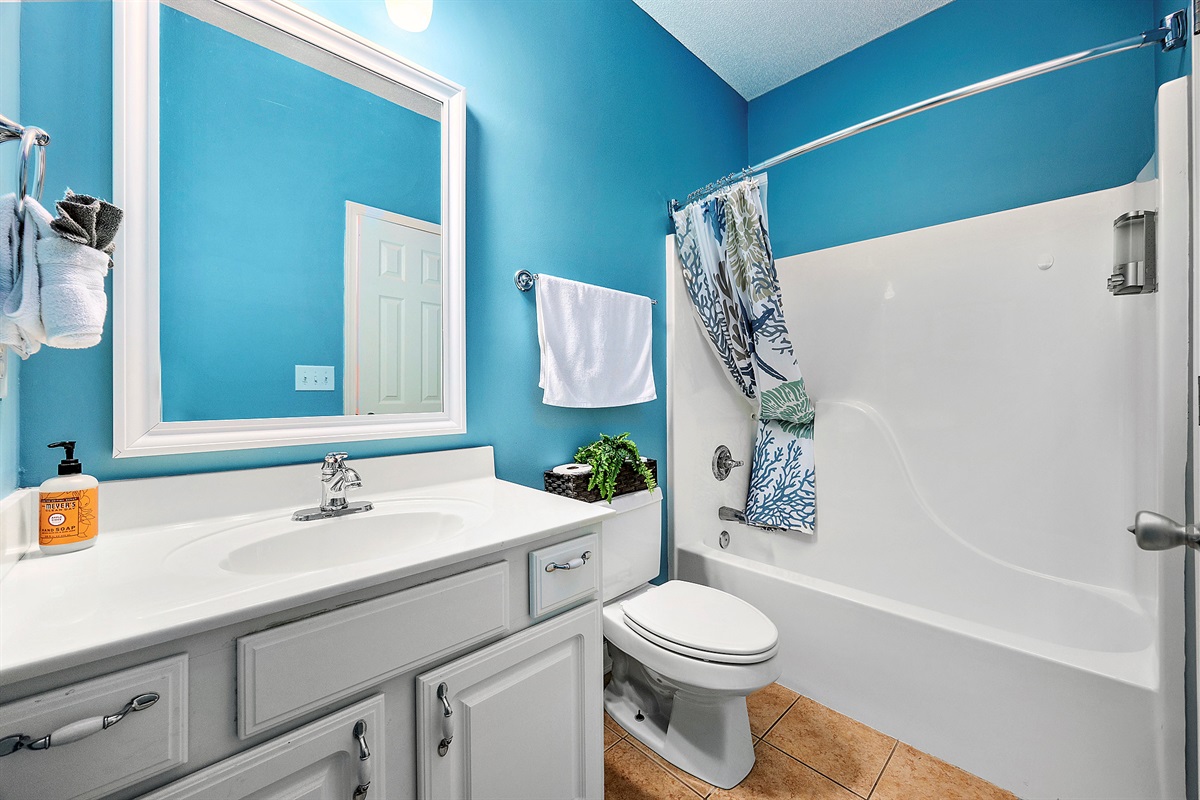 [Bedroom] - The coastal blue walls and nautical details continue throughout this thoughtfully designed bathroom, creating a cohesive beach retreat experience.