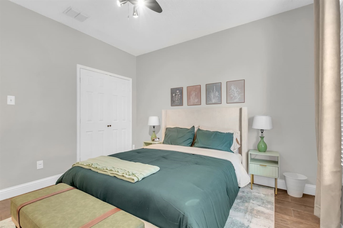 Comfortable guest bedroom offering a queen bed, room-darkening blinds, ceiling fan, fresh linens, and a guest-ready layout for family or group stays.