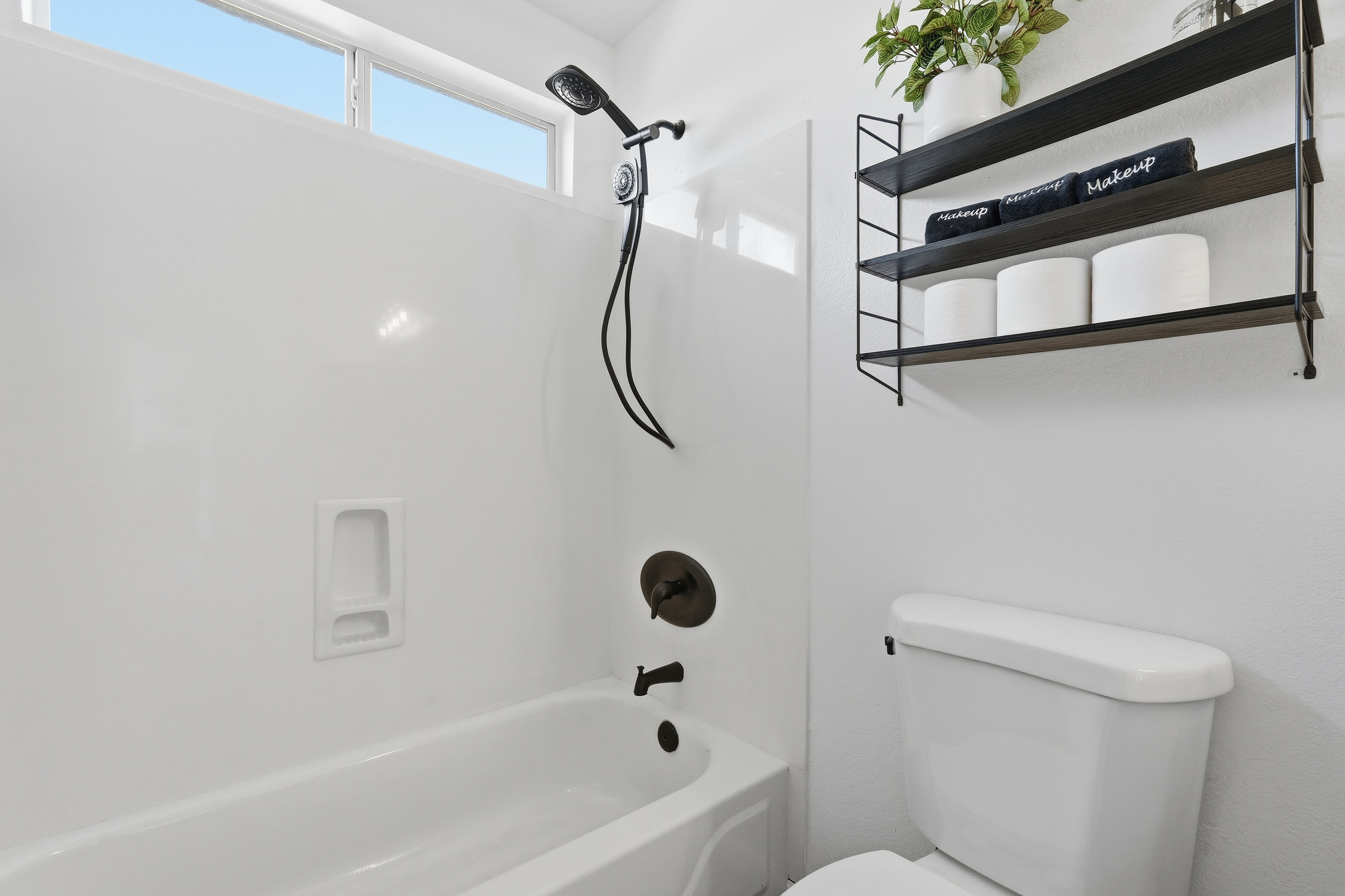 Full Bathroom 2 with a shower/tub combination, handheld showerhead, and wall shelf stocked with extra bath essentials.