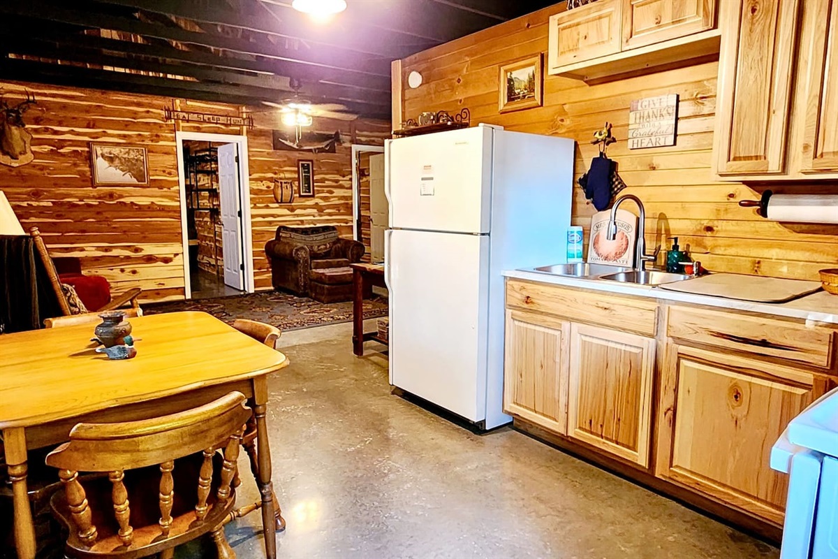 The heart of the lodge features a fully equipped kitchen with knotty pine cabinets, full-size fridge, stove, and coffee maker. Enjoy cozy meals at the vintage dining table, just steps from the living area’s comfy chairs and warm cabin charm.