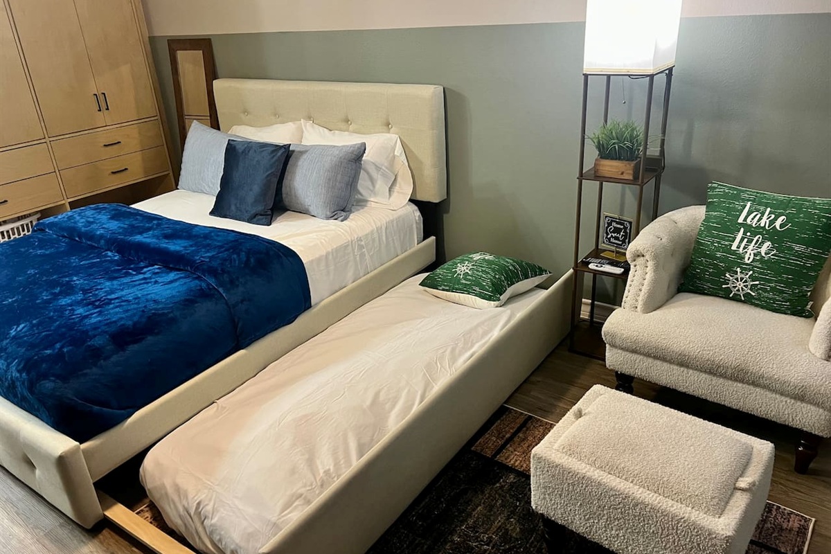 Queen bed with a twin pull-out underneath, plus a chair and ottoman for relaxing.
