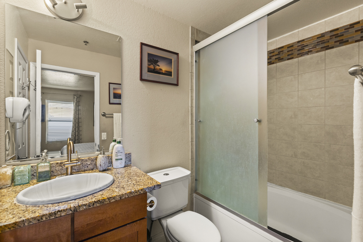 Bathroom 1 with granite vanity, tub/shower combo, and sliding glass shower doors.
