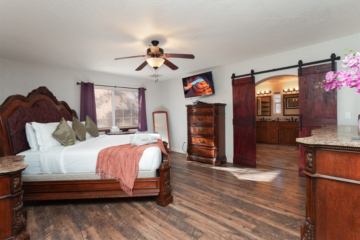 Spacious king suite designed for true relaxation—comfortable bedding, warm wood accents, and direct access to the spa-like ensuite bathroom.