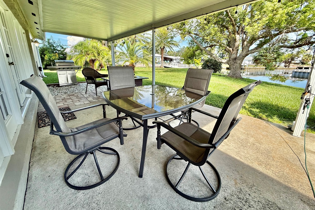 This peaceful covered patio offers the perfect mix of sun and shade, with plenty of seating, a grill for cookouts, and views of lush greenery all around.