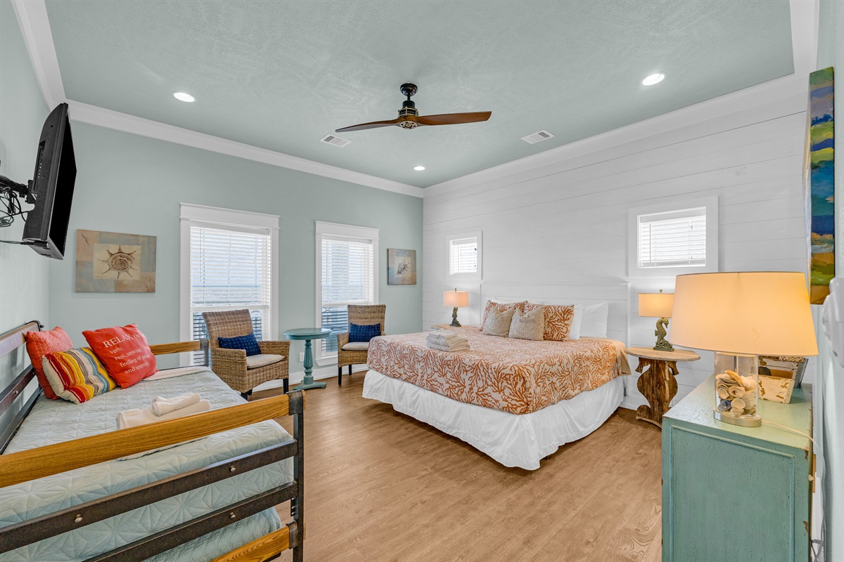Sea It All: Primary bedroom is well appointed, with a twin trundle bed, added seating, a SMART TV, and plenty of natural light. 