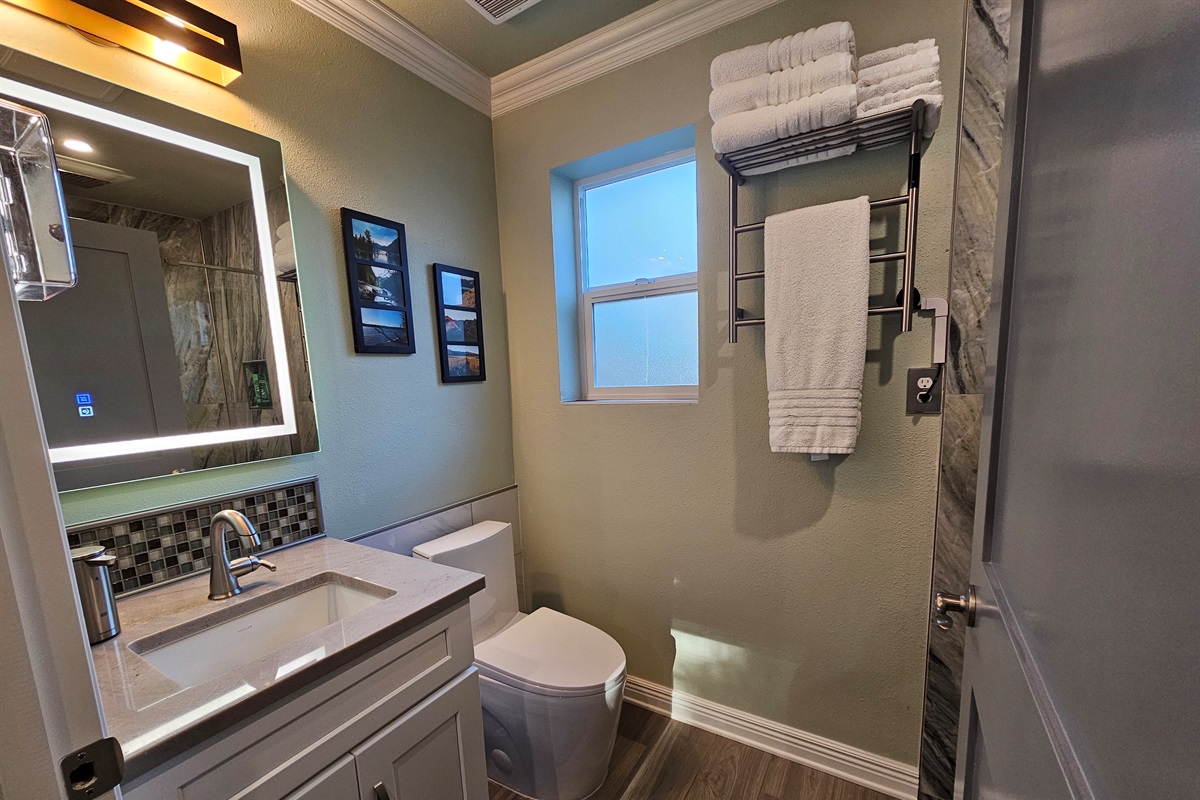 En suite with lighted mirror, heated towel warmer, and pull down sprayer for sink.