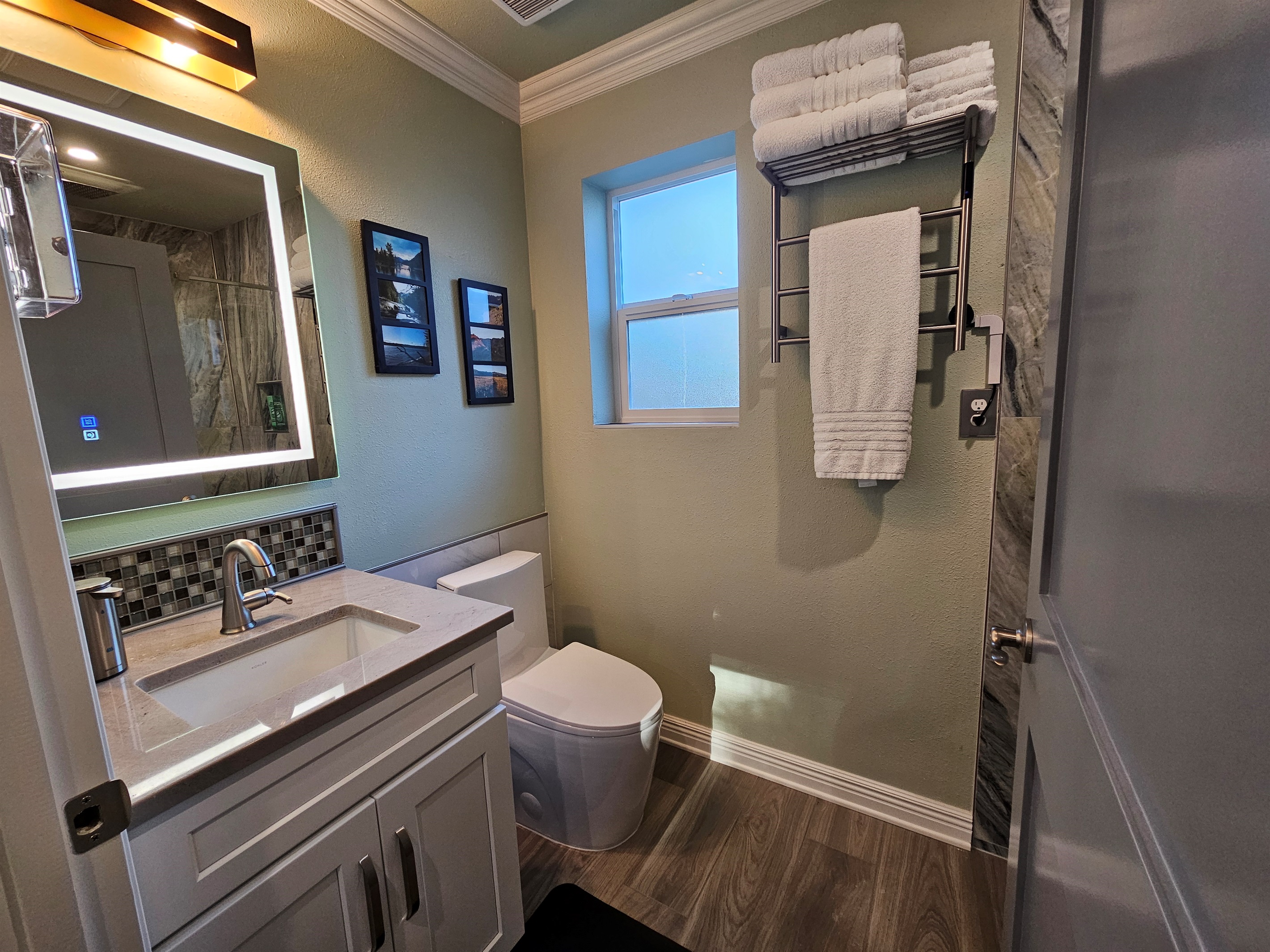 En suite with lighted mirror, heated towel warmer, and pull down sprayer for sink.