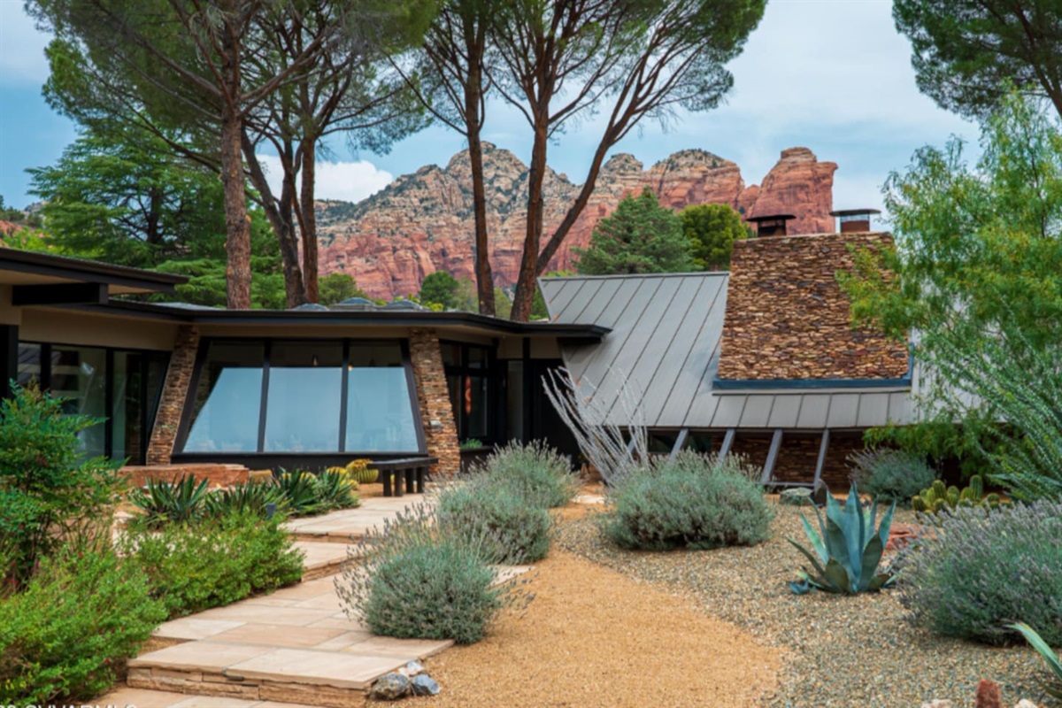 Beautifully landscaped courtyard with native desert plants and striking red rock views surrounding the modern architecture.