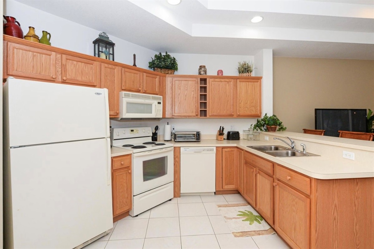 Spacious kitchen with full-size appliances, plenty of cabinet storage, tile flooring, and an open breakfast bar layout.