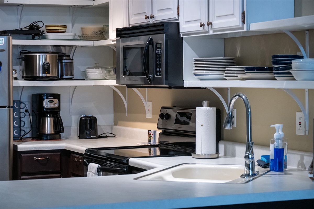 Well-stocked kitchen with coffee maker, cookware, dishes, and essentials for convenient vacation dining.