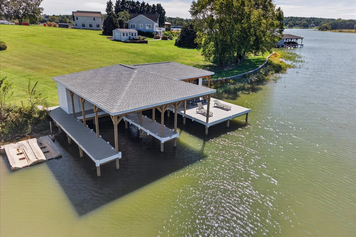 Private boathouse with multiple covered slips and an oversized deck extending over the water.