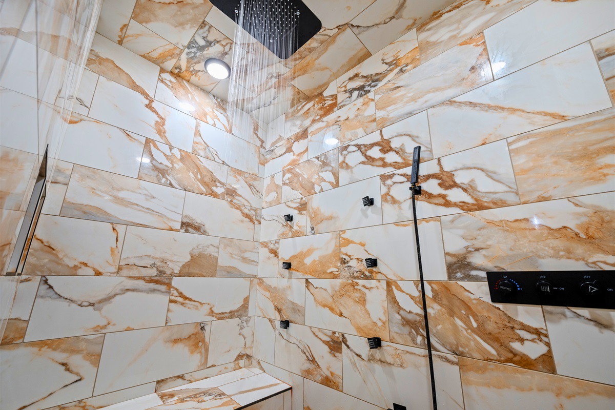 Walk-in shower with custom tile and forest-inspired stonework.