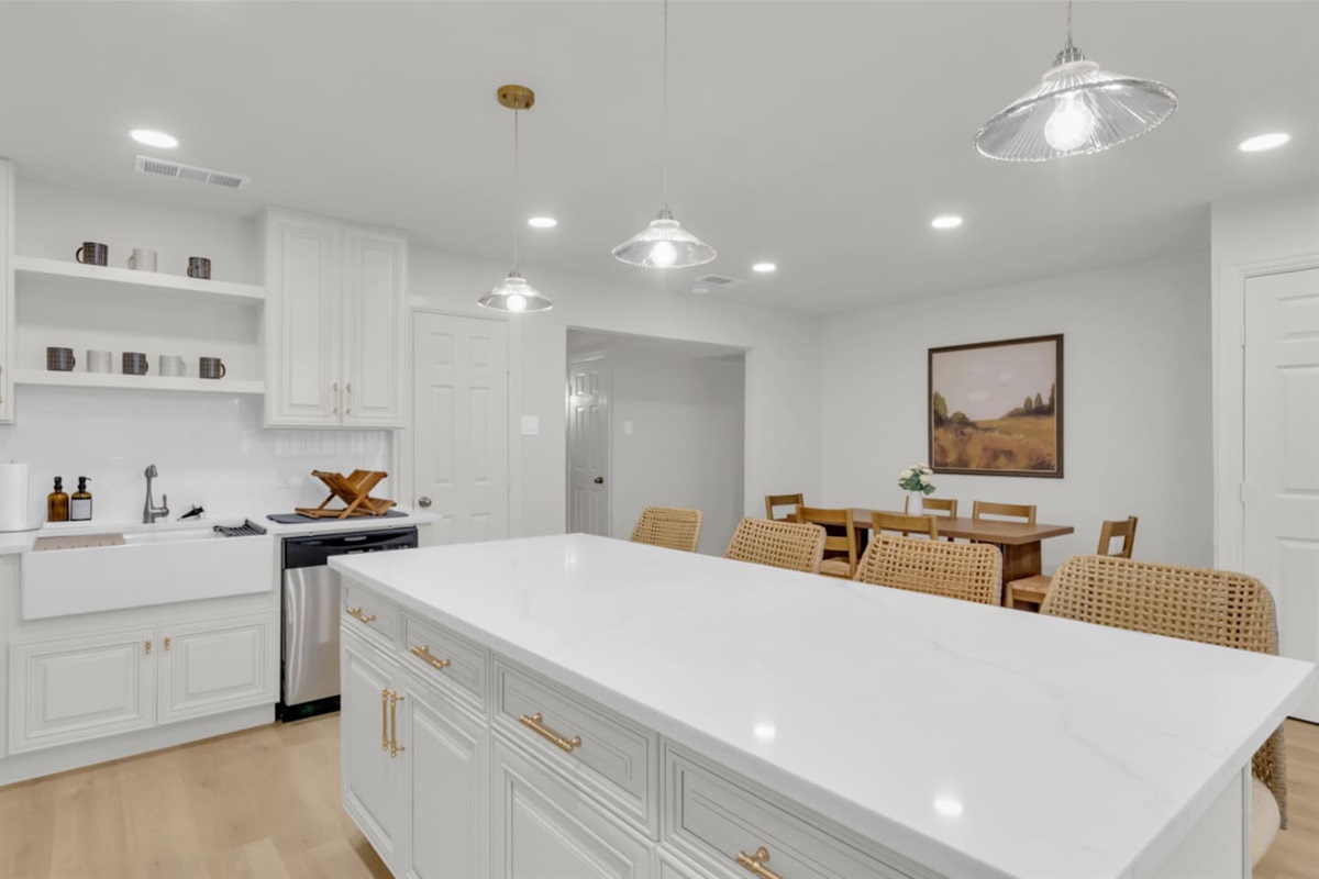 Spacious island with bar seating for four, ideal for gathering and meal prep. Steps from the dining table, private living room, and open kitchen layout.