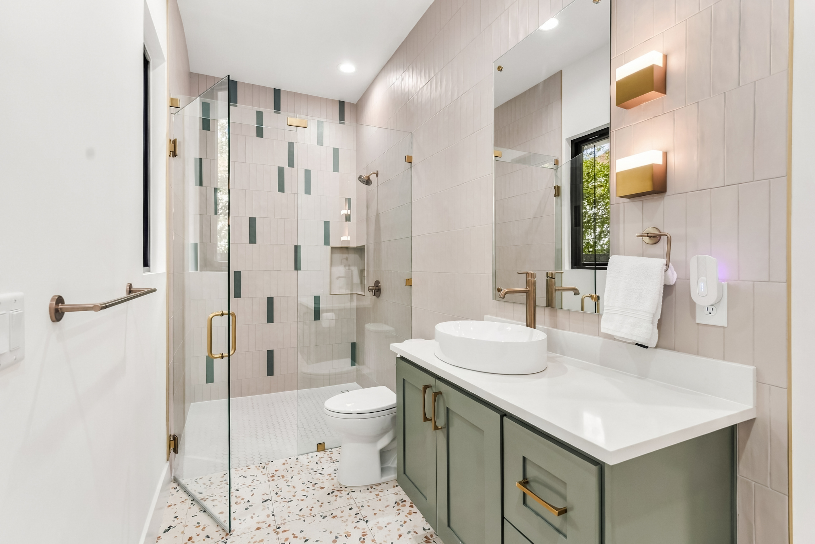Green mosaic tile and a vessel sink vanity add character to this bathroom.