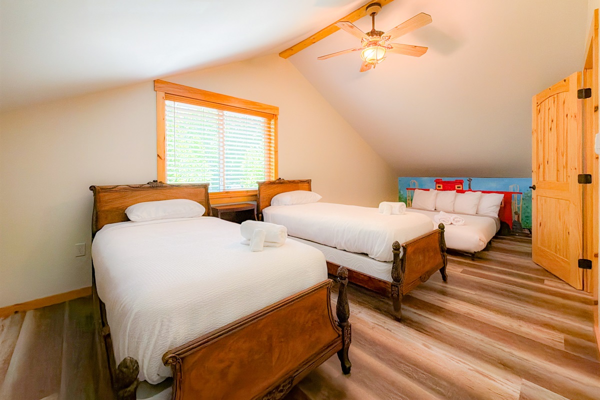 The Caboose themed room is setup for the kiddos who two twin beds na da low profile Queen Bed with a handprinted train backdrop.