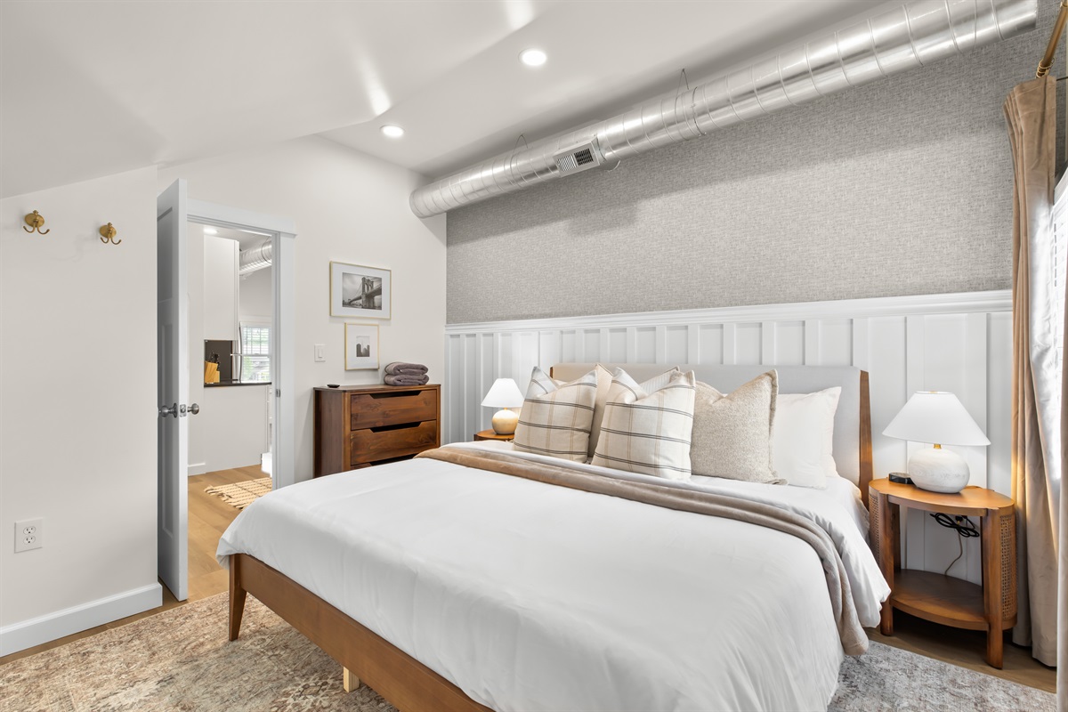 Rest easy in this stylish bedroom featuring a plush king bed, modern lighting, and calming neutral tones