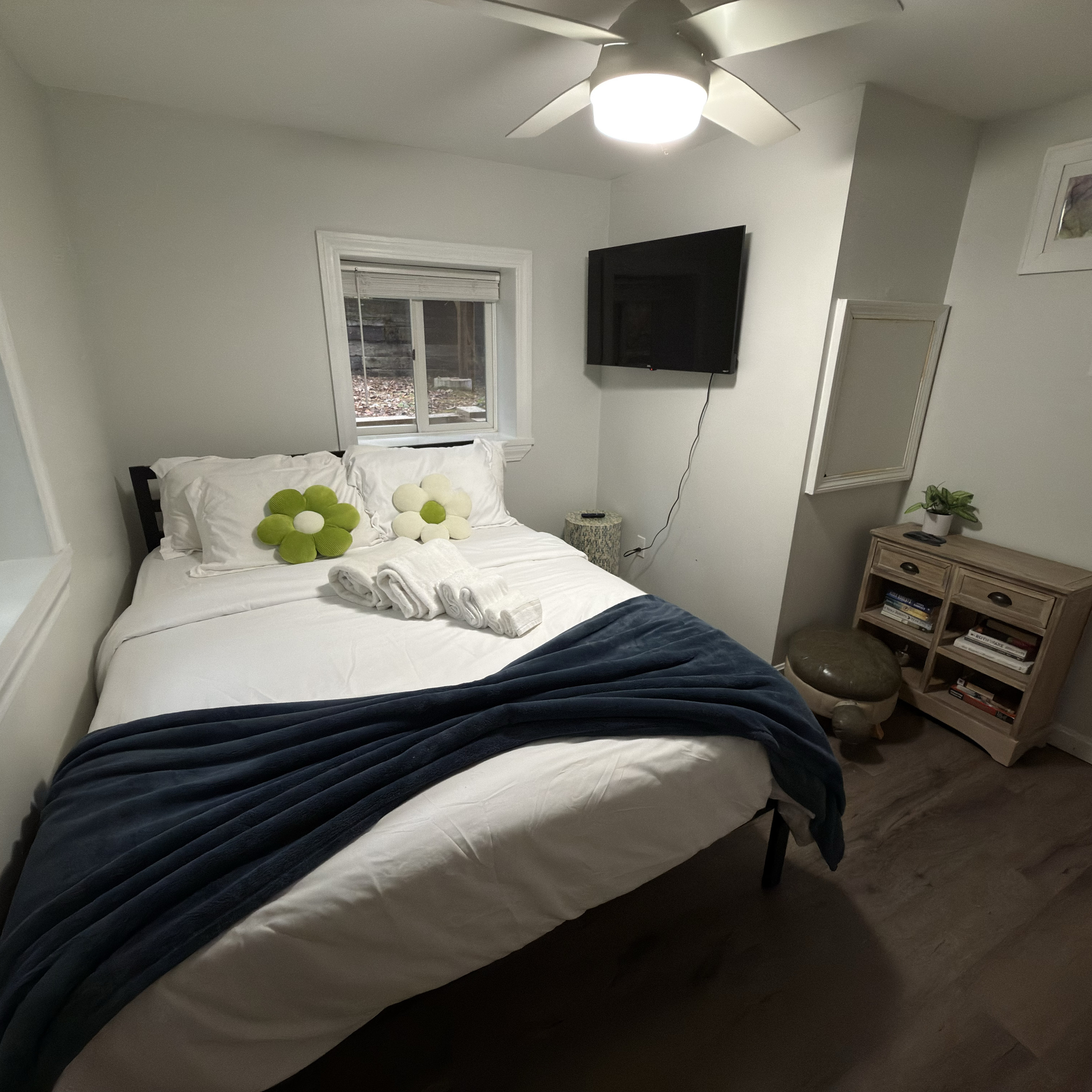 Another view of the queen bedroom featuring a wall-mounted TV and a selection of books for a relaxing night in.