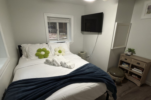Another view of the queen bedroom featuring a wall-mounted TV and a selection of books for a relaxing night in.