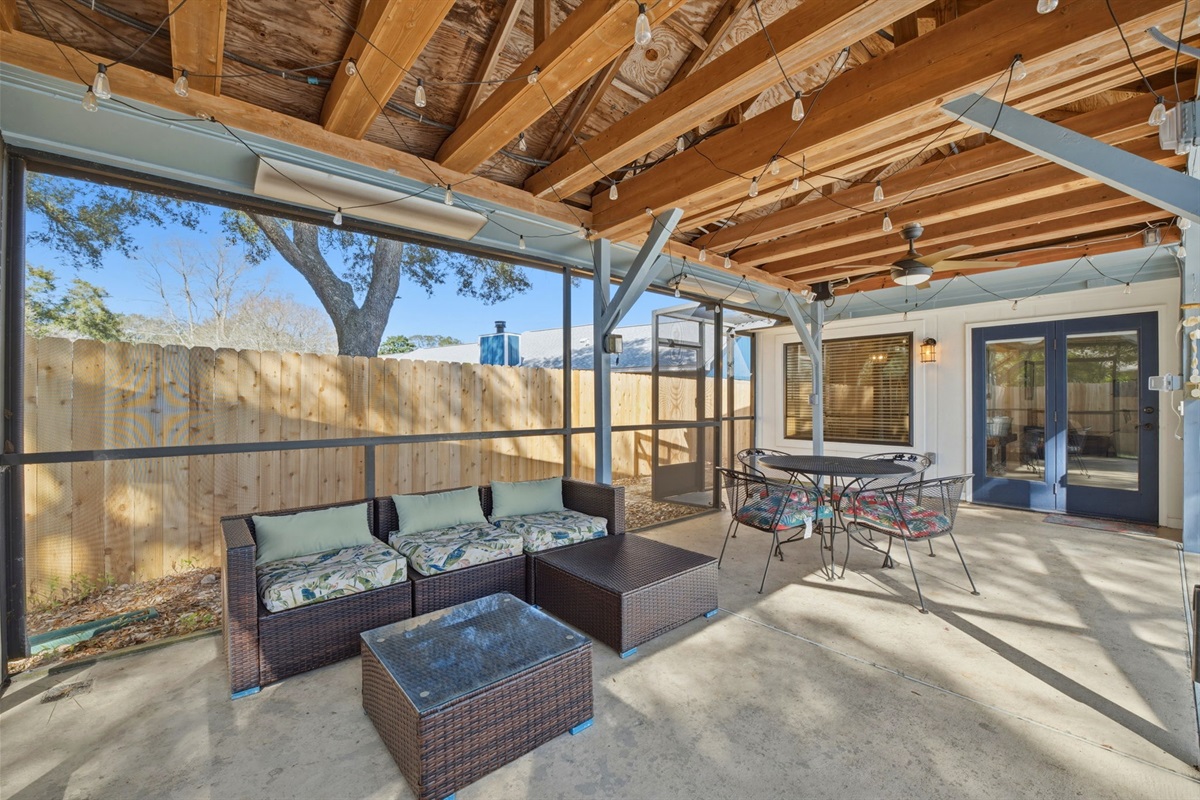 This inviting screened patio offers a comfortable outdoor retreat with cozy seating, dining space, and warm wood ceiling details. Just steps away, the fenced pool area provides a refreshing escape for a  safe, relaxing environment for family & friends.
