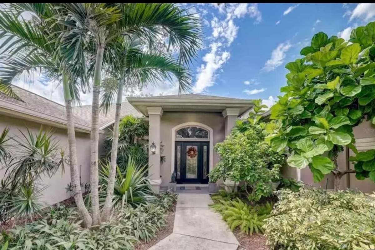 Welcoming front entry framed by lush greenery.