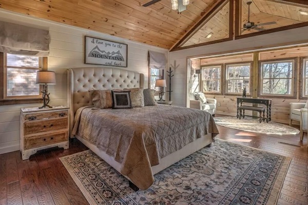 Primary bedroom retreat with vaulted wood ceilings, plush bedding, and peaceful forest views.