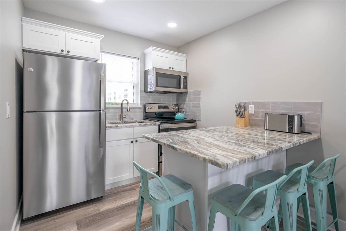 Clean, well equipped kitchen with stainless steel appliances, stone countertops, and a generous island with seating. The bright layout offers plenty of space for preparing meals, enjoying casual breakfasts, or gathering after a day out.