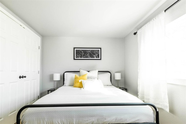 The bright queen bedroom combines comfort and style, featuring soft linens and natural light for a tranquil ambiance.