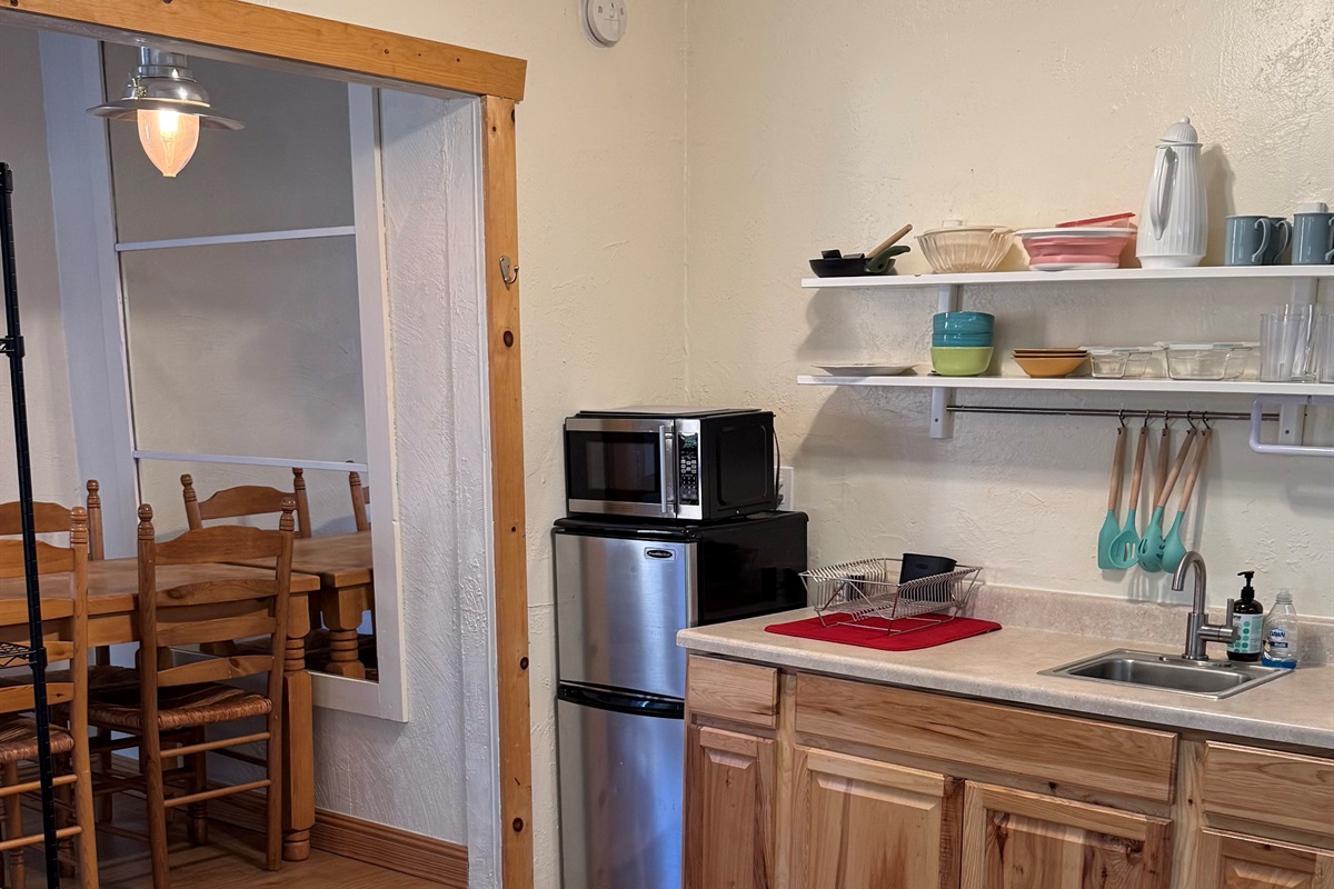 Compact kitchenette with essential cookware, mini fridge, and microwave, plus direct access to the dining area for convenient meals and gatherings