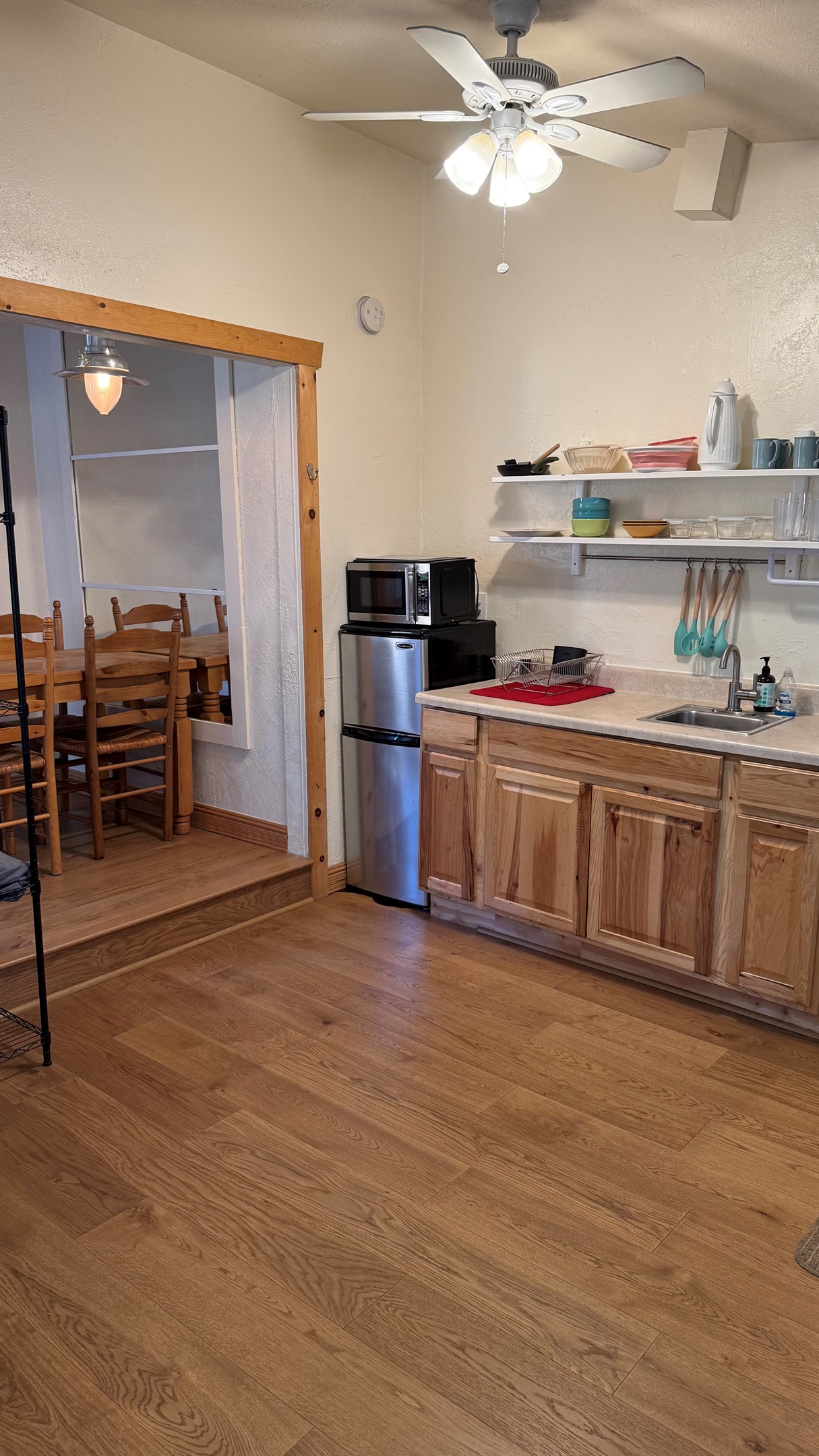 Compact kitchenette with essential cookware, mini fridge, and microwave, plus direct access to the dining area for convenient meals and gatherings