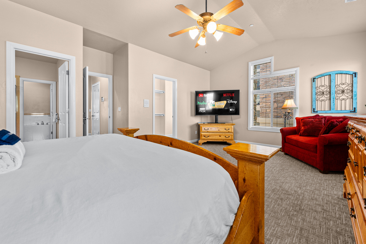 Spacious primary bedroom with California king bed, cozy seating, and plenty of natural light.