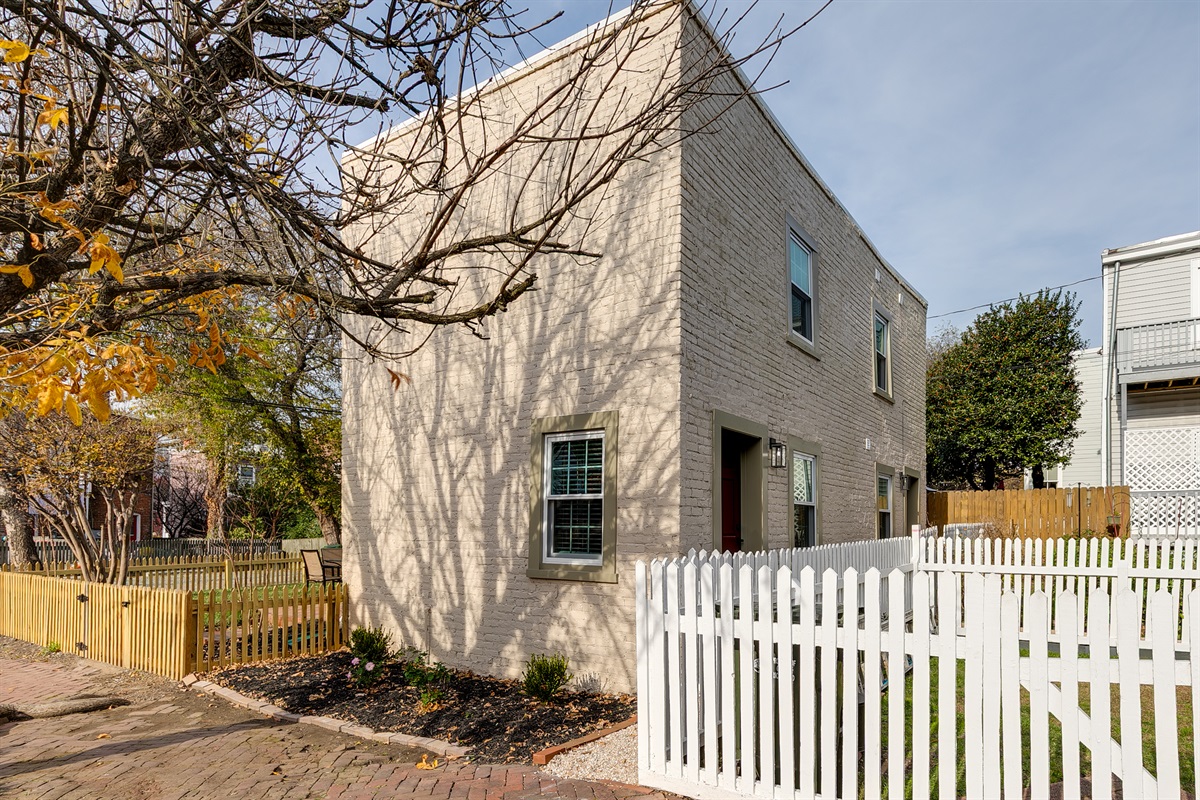 Charming Exterior: Bright, welcoming façade with a white picket fence and lush greenery awaits!