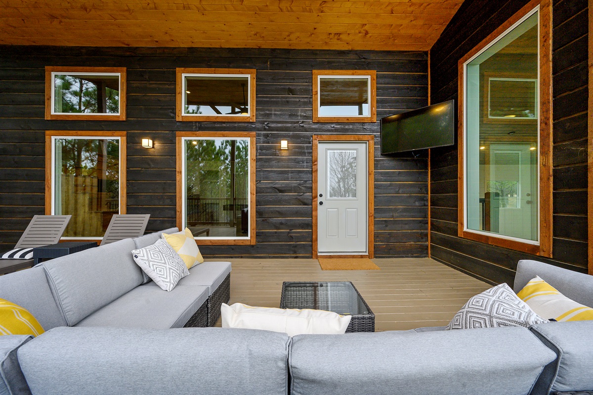 A cozy patio setup featuring lounge seating and an outdoor TV for easy, laid-back entertainment outside.