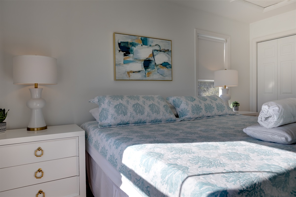 Spacious and serene, upstairs master features a comfortable King-size bed with plush bedding, soft coastal d&eacute;cor, and ample natural light