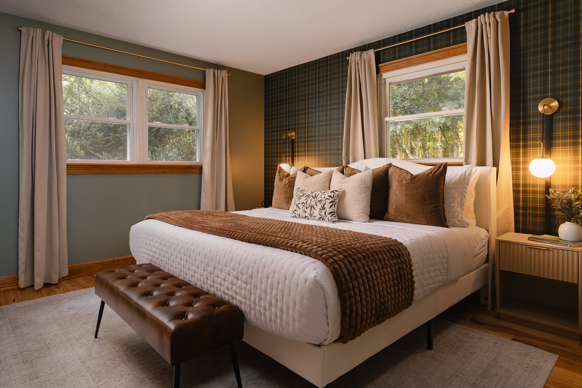 {Bedroom 1} Settle into the king bed in this moody, thoughtfully designed retreat with warm textures and windows overlooking the forest.