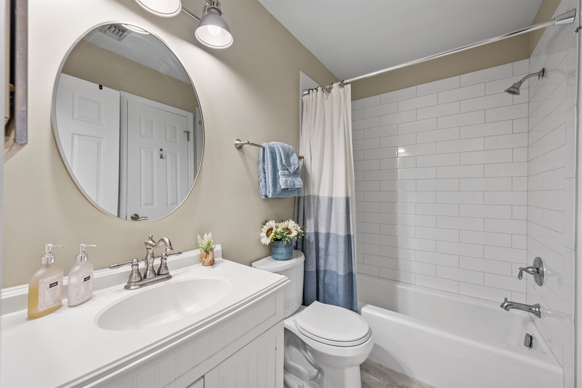 Master bathroom featuring a full shower/tub combo, updated fixtures, and fresh coastal touches