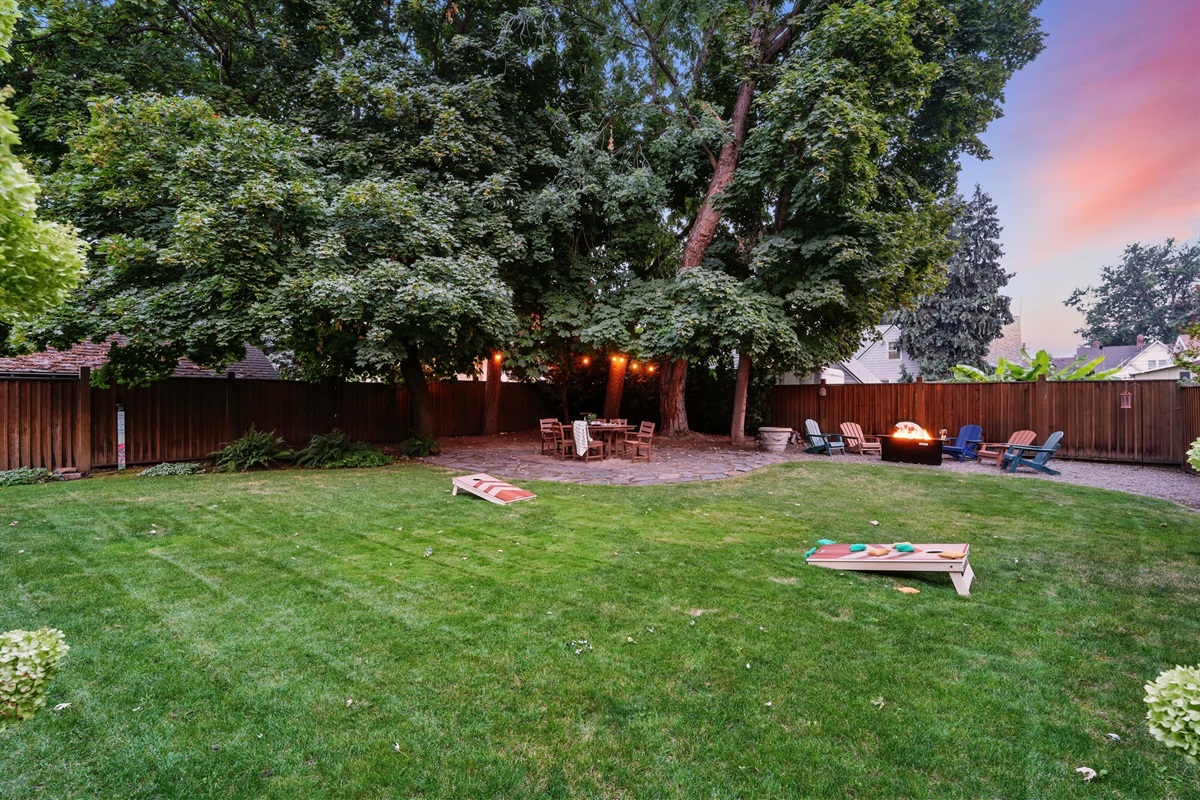 Large backyard with a park-like setting, outdoor dining for 6, corn hole, and 6 lounge chairs gathered around the fire table (propane provided)